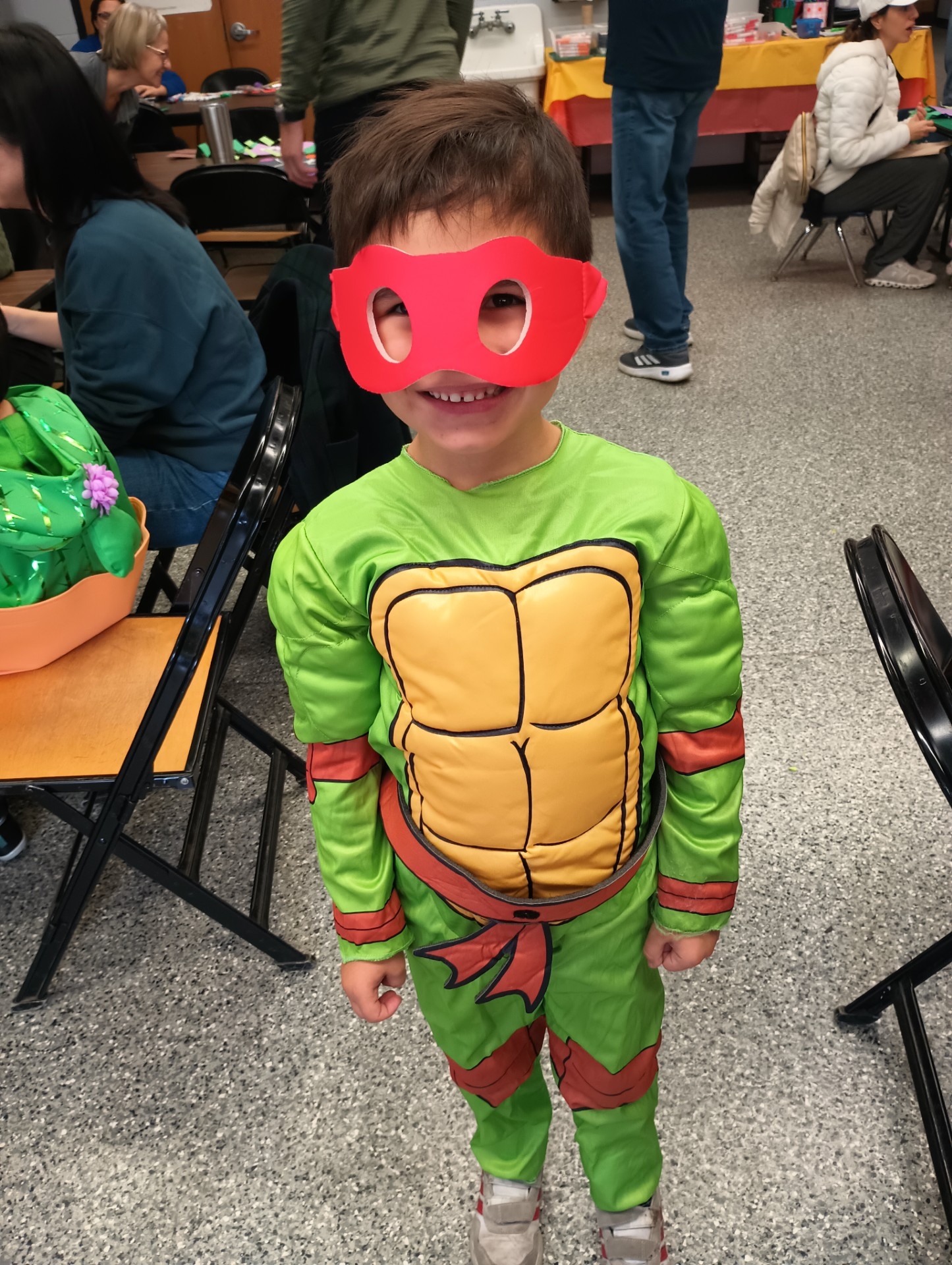 A smiling child in a Raphael Ninja Turtle costume.